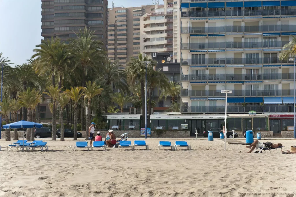 Foto de la playa con turistas en las tumbonas y el Hotel Palmeral al fondo